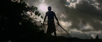 Movie still from “Karnan” (2021), directed by Mari Selvaraj – A man standing on top of a hill holding a sword; Wide shot, Low angle
