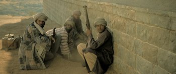Movie still from “Kesari” (2019), directed by Anurag Singh – A group of men sitting next to each other holding guns; Medium shot, High angle
