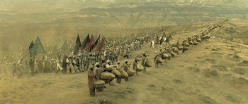 Movie still from “Kesari” (2019), directed by Anurag Singh – A large group of people marching down a dirt road; Extreme Wide shot, High angle