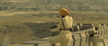 Movie still from “Kesari” (2019), directed by Anurag Singh – A man in a turban is standing on a ledge; Medium shot, High angle