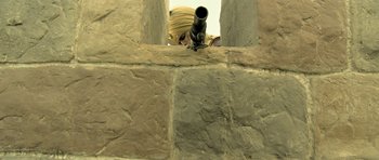 Movie still from “Kesari” (2019), directed by Anurag Singh – A woman looking through a telescope on a brick wall; Extreme Close Up shot, Low angle