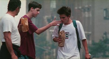 Movie still from “Kids” (1995), directed by Larry Clark – Two young men standing next to each other on a city street; Medium shot, Over the shoulder angle