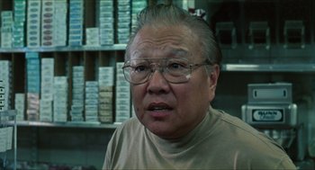 Movie still from “Kids” (1995), directed by Larry Clark – An older man wearing glasses in front of a wall of boxes; Close Up shot, Low angle