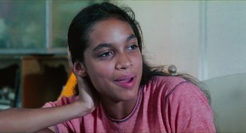 Movie still from “Kids” (1995), directed by Larry Clark – A young girl is sitting down with her hand behind her head; Close Up shot, High angle