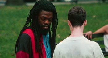 Movie still from “Kids” (1995), directed by Larry Clark – A man with dreads talking to another man in a park; Medium shot, Over the shoulder angle