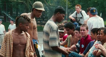 Movie still from “Kids” (1995), directed by Larry Clark – A group of young men sitting around each other on the ground; Medium shot, Over the shoulder angle