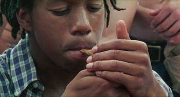 Movie still from “Kids” (1995), directed by Larry Clark – A person is eating a marijuana joint; Close Up shot, Overhead angle