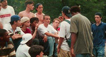 Movie still from “Kids” (1995), directed by Larry Clark – A group of young men sitting on the ground talking; Medium shot, High angle