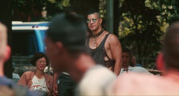 Movie still from “Kids” (1995), directed by Larry Clark – A man in a black tank top is standing in front of a group of people; Medium shot, Over the shoulder angle