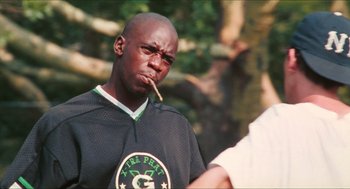 Movie still from “Kids” (1995), directed by Larry Clark – A young man smoking a cigarette while wearing a black shirt; Medium shot, Low angle