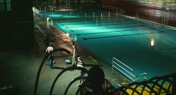 Movie still from “Kids” (1995), directed by Larry Clark – A group of people standing around a pool at night; Extreme Wide shot, High angle