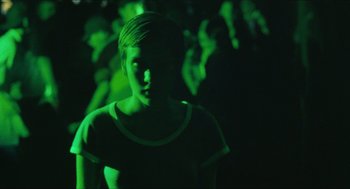 Movie still from “Kids” (1995), directed by Larry Clark – A woman is standing in a dark room with green lights; Medium shot, High angle
