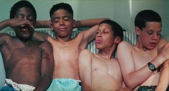Movie still from “Kids” (1995), directed by Larry Clark – Two young men laying on a bed with their arms behind their heads; Medium shot, Overhead angle