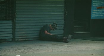Movie still from “Kids” (1995), directed by Larry Clark – A man sitting on the ground on the sidewalk; Wide shot, Low angle