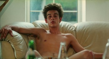 Movie still from “Kids” (1995), directed by Larry Clark – A man sitting on a couch next to a beer bottle; Medium shot, High angle
