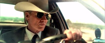Movie still from “Kill Bill: Vol. 1” (2003), directed by Quentin Tarantino – A man in a cowboy hat and sunglasses driving a car; Close Up shot, Low angle