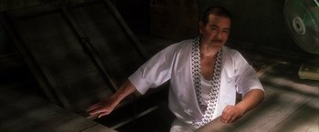 Movie still from “Kill Bill: Vol. 1” (2003), directed by Quentin Tarantino – An older man wearing a chain around his neck; Close Up shot, Low angle