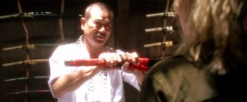 Movie still from “Kill Bill: Vol. 1” (2003), directed by Quentin Tarantino – A man is holding a red object in his hands; Close Up shot, Over the shoulder angle