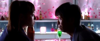 Movie still from “Kill Bill: Vol. 1” (2003), directed by Quentin Tarantino – A woman and a man face to face with a glass of wine in front of them; Close Up shot, Over the shoulder angle