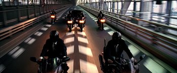 Movie still from “Kill Bill: Vol. 1” (2003), directed by Quentin Tarantino – A group of people on motorcycles driving down a street; Wide shot, High angle