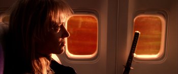 Movie still from “Kill Bill: Vol. 1” (2003), directed by Quentin Tarantino – A woman looking out of an airplane window at sunset; Close Up shot, Over the shoulder angle