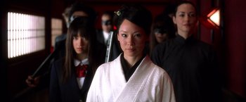 Movie still from “Kill Bill: Vol. 1” (2003), directed by Quentin Tarantino – A group of young people standing around a woman in a kimono; Close Up shot, Over the shoulder angle