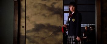 Movie still from “Kill Bill: Vol. 1” (2003), directed by Quentin Tarantino – A woman in a school uniform standing in front of an open door; Medium shot, Low angle