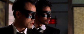 Movie still from “Kill Bill: Vol. 1” (2003), directed by Quentin Tarantino – Two men in suits and black masks looking at the camera; Close Up shot, Low angle