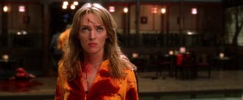 Movie still from “Kill Bill: Vol. 1” (2003), directed by Quentin Tarantino – A woman in a yellow and orange shirt with blood on her face; Close Up shot, Low angle