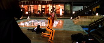 Movie still from “Kill Bill: Vol. 1” (2003), directed by Quentin Tarantino – A woman in a yellow outfit is holding a sword; Wide shot, Low angle