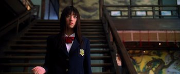 Movie still from “Kill Bill: Vol. 1” (2003), directed by Quentin Tarantino – A woman in a suit and tie standing in front of a staircase; Close Up shot, Low angle