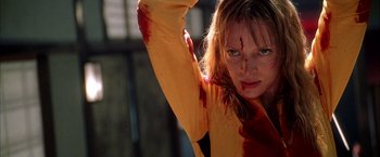 Movie still from “Kill Bill: Vol. 1” (2003), directed by Quentin Tarantino – A woman in a yellow shirt with blood all over her face; Close Up shot, Low angle