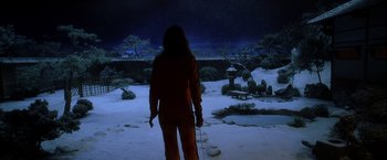 Movie still from “Kill Bill: Vol. 1” (2003), directed by Quentin Tarantino – A person standing in the snow holding a stick; Wide shot, High angle