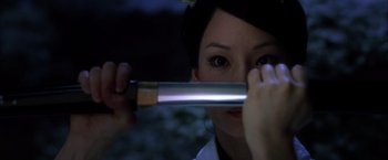 Movie still from “Kill Bill: Vol. 1” (2003), directed by Quentin Tarantino – A woman holding a knife up to her face; Close Up shot, Over the shoulder angle