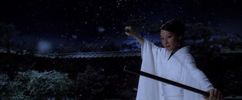 Movie still from “Kill Bill: Vol. 1” (2003), directed by Quentin Tarantino – A woman in a white robe holding a sword in front of a night sky; Medium shot, Low angle