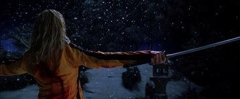 Movie still from “Kill Bill: Vol. 1” (2003), directed by Quentin Tarantino – A man holding a sword in front of a snow covered sky; Medium shot, Low angle