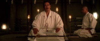 Movie still from “Kill Bill: Vol. 1” (2003), directed by Quentin Tarantino – A man sitting in front of candles in a room; Medium shot, Low angle