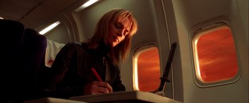 Movie still from “Kill Bill: Vol. 1” (2003), directed by Quentin Tarantino – A woman writing on a piece of paper on top of an airplane; Close Up shot, Low angle