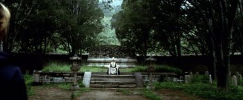 Movie still from “Kill Bill: Vol. 2” (2004), directed by Quentin Tarantino – A man sitting on steps in the middle of a forest; Extreme Wide shot, Low angle