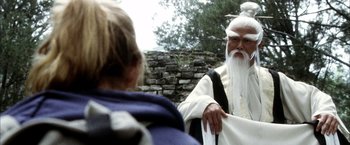 Movie still from “Kill Bill: Vol. 2” (2004), directed by Quentin Tarantino – An old man with long white hair and a white beard is talking to a young girl; Medium shot, Over the shoulder angle