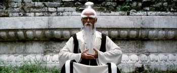 Movie still from “Kill Bill: Vol. 2” (2004), directed by Quentin Tarantino – An old man with a long white beard wearing a black and white outfit; Medium shot, Low angle