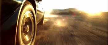 Movie still from “Kill Bill: Vol. 2” (2004), directed by Quentin Tarantino – A car driving down a dirt road in the desert; Wide shot, Low angle