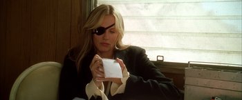 Movie still from “Kill Bill: Vol. 2” (2004), directed by Quentin Tarantino – A woman wearing a pirate eye patch holding a notebook; Close Up shot, Over the shoulder angle