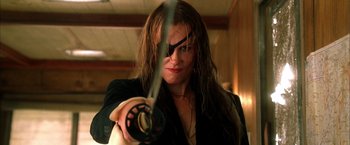 Movie still from “Kill Bill: Vol. 2” (2004), directed by Quentin Tarantino – A woman holding a sword in a dark room; Close Up shot, Low angle