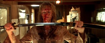 Movie still from “Kill Bill: Vol. 2” (2004), directed by Quentin Tarantino – A woman is holding a knife with blood all over her face; Medium shot, Low angle