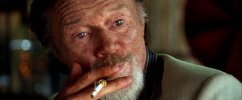 Movie still from “Kill Bill: Vol. 2” (2004), directed by Quentin Tarantino – An old man with a beard smoking a cigarette; Close Up shot, Overhead angle