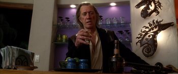 Movie still from “Kill Bill: Vol. 2” (2004), directed by Quentin Tarantino – A man sitting at a table with a glass of wine; Close Up shot, Low angle