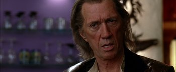 Movie still from “Kill Bill: Vol. 2” (2004), directed by Quentin Tarantino – An older man with long hair and wearing a leather jacket; Close Up shot, Over the shoulder angle