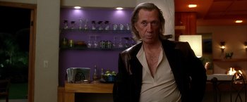 Movie still from “Kill Bill: Vol. 2” (2004), directed by Quentin Tarantino – A man with long white hair standing in front of a counter; Medium shot, Low angle