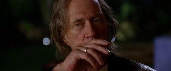 Movie still from “Kill Bill: Vol. 2” (2004), directed by Quentin Tarantino – An older man smoking a cigarette with a ring on his finger; Close Up shot, Low angle